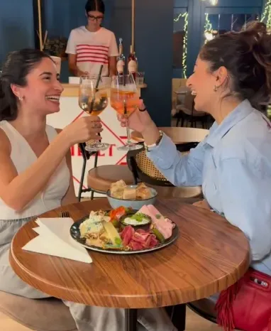 Deux amies trinquent autour d'une planche apéritive