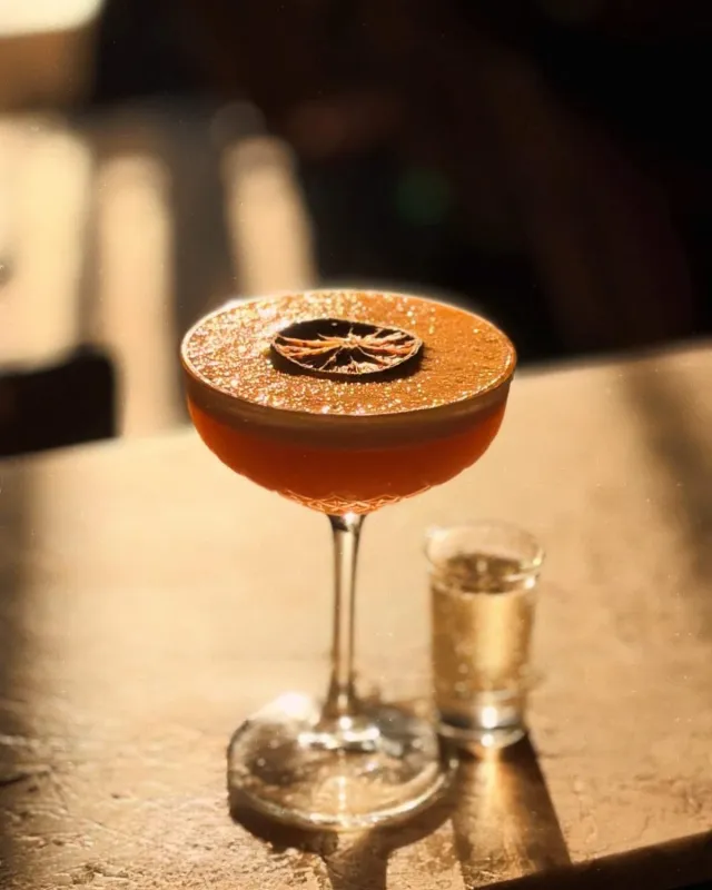 Cocktail ambré en coupe, mousse pailletée et orange séchée
