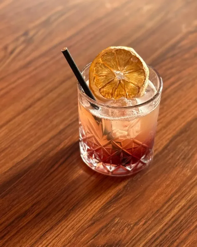 Cocktail rouge et orangé sur glace, rondelle d'orange séchée