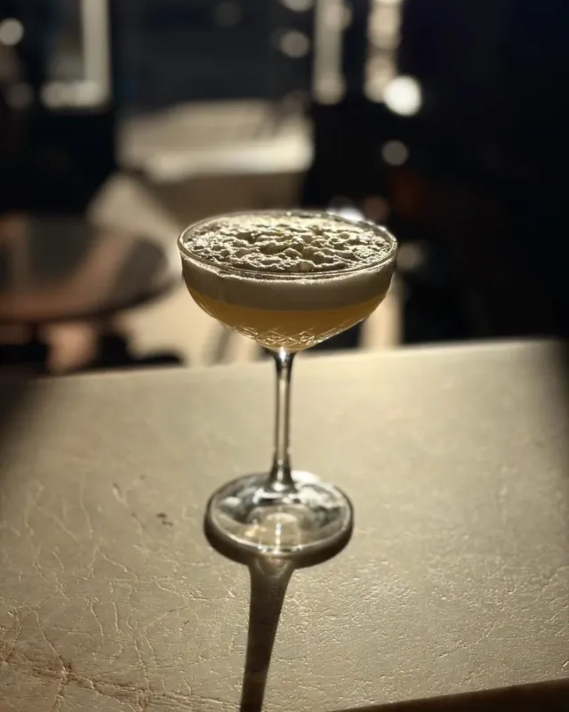 Cocktail doré en coupe ciselée, surmonté d'une mousse