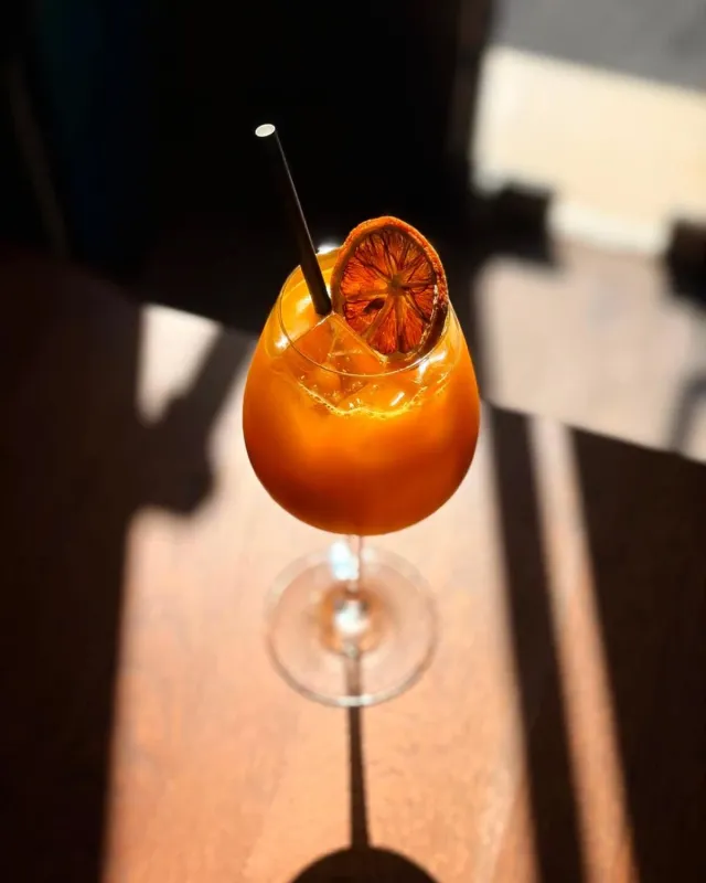 Cocktail orangé garni d'une rondelle d'orange séchée, en plein soleil